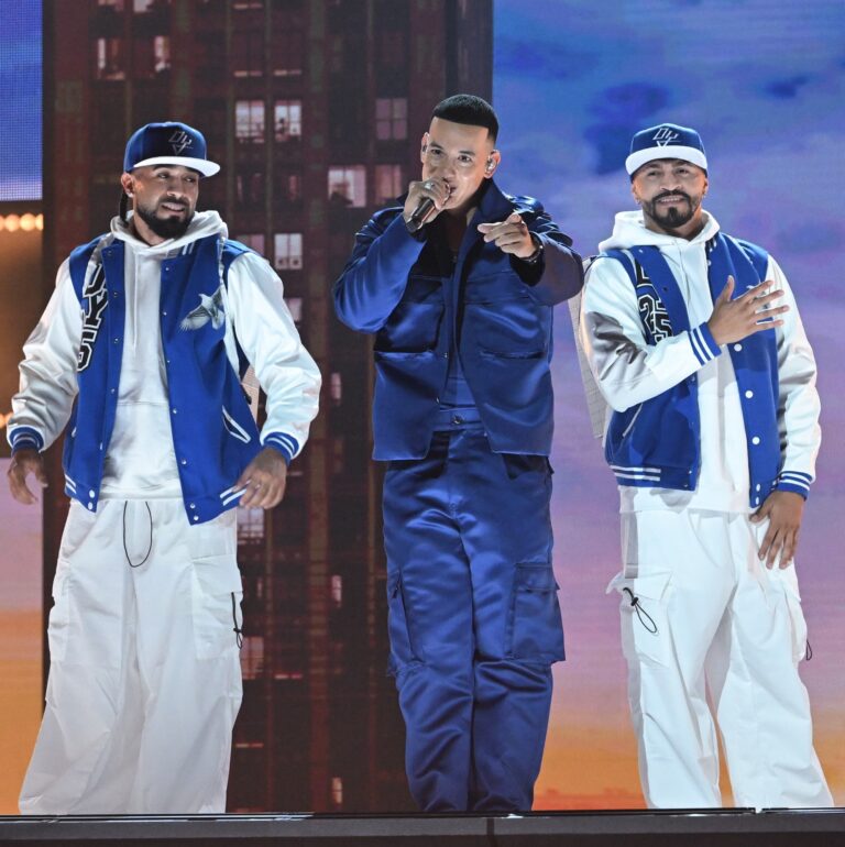 Man performing on stage with backing dancers behind him