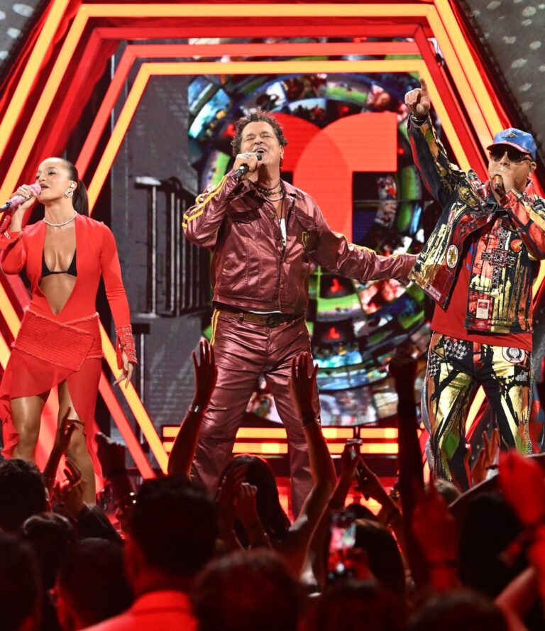 Man performing on stage with dancers behind him